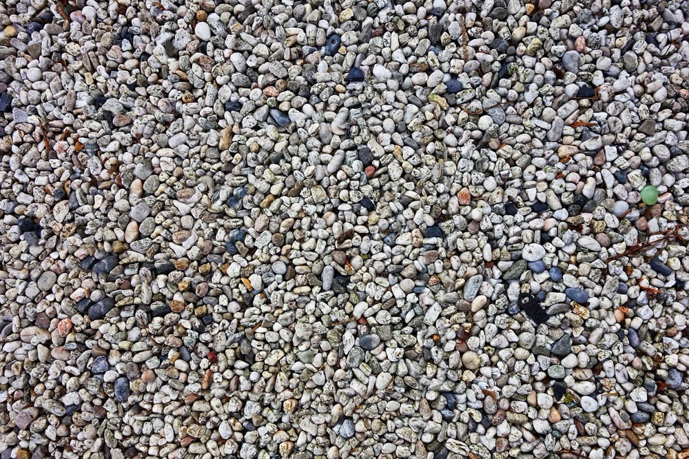Close-up of loose pea gravel: small, smooth, rounded stones in white, gray, tan and blue-gray